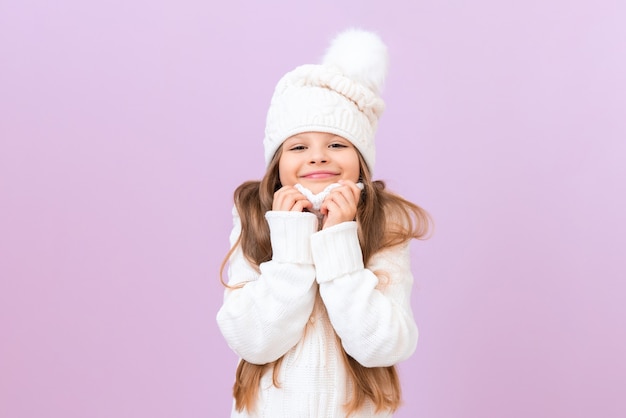 El niño se está calentando con un suéter caliente. Una niña con un sombrero de invierno blanco está feliz y sonriente.
