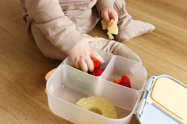 un niño está comiendo una fresa y una caja de fresas