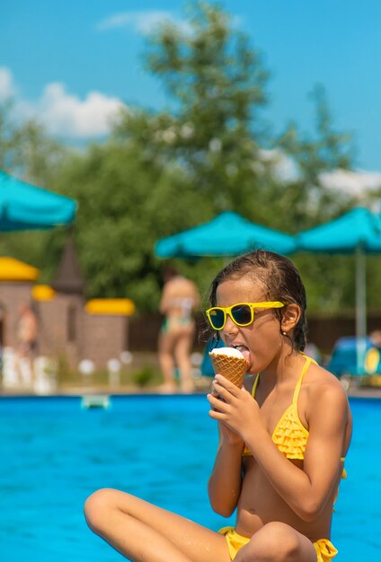 El niño está comiendo helado cerca de la piscina. Enfoque selectivo. Niño.