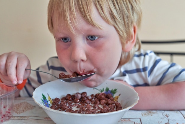 Niño está desayunando con bolas de chocolate con leche