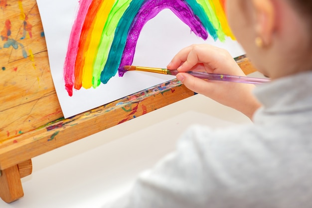 El niño está dibujando un arco iris.