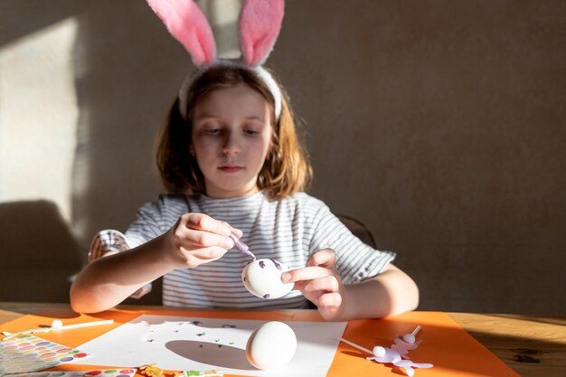 El niño está haciendo la preparación de la decoración de los huevos de pascua y la niña funcute en las orejas de los conejitos de pascua se prepara