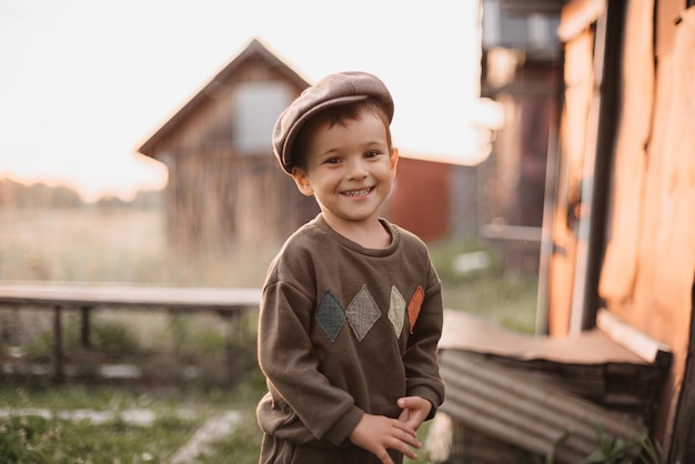 Un niño está jugando en un campo de granja o rancho descansando Retrato de un niño pequeño con una gorra y un mono Infancia Una imagen auténtica con emociones sinceras