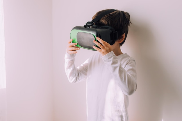 Un niño está jugando con gafas vr en una pared blanca de copyspace Un artículo sobre dispositivos modernos Un artículo sobre tecnologías modernas