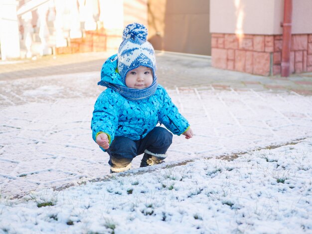 Un niño está jugando en la nieve. 0-1 niño, un niño jugando con nieve en terreno nevado. caminando en un parque nevado disfrutando de la primera nevada