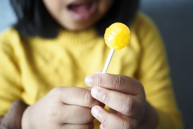 El niño está lamiendo dulces coloridos en un palo