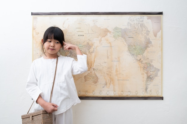 Un niño está pensando frente al mapa mundial.