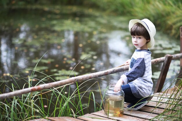 Un niño está pescando en la mañana de otoño Atardecer de otoño en el estanque Un pescador con una caña de pescar en la pasarela