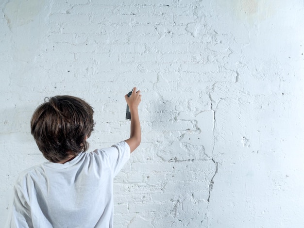 Un niño está pintando una pared con una lata de spray