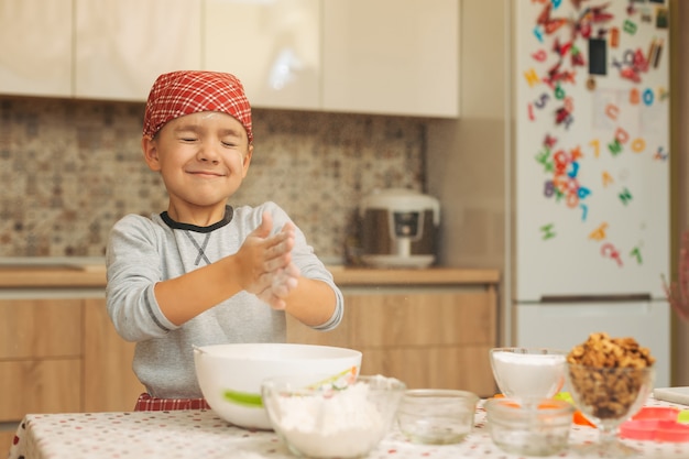 El niño está preparando la masa, hornea galletas en la cocina