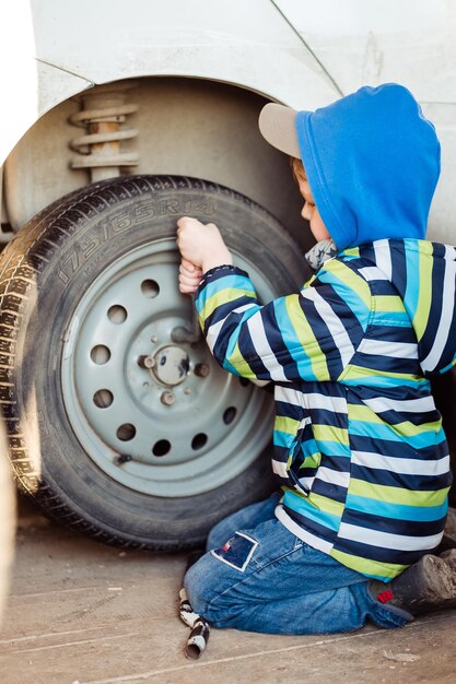 El niño está reparando el coche El niño está cambiando la rueda