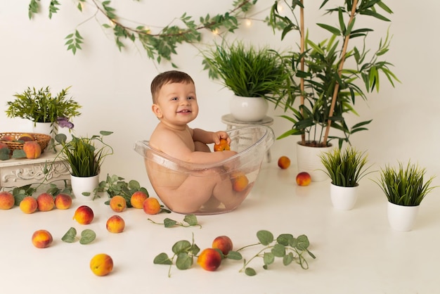 Un niño está sentado en el baño sobre un fondo blanco con melocotones y se regocija.