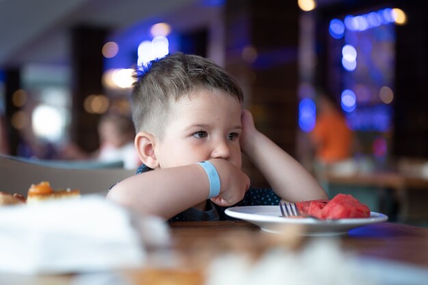 El niño está sentado solo en un restaurante.