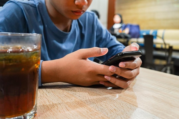 El niño está sosteniendo un teléfono inteligente jugando con el teléfono de la mano sosteniendo un teléfono celular en la mesa