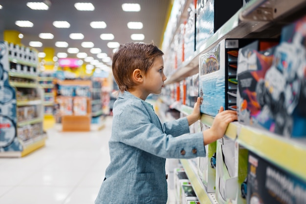 Niño en la estantería de la tienda para niños