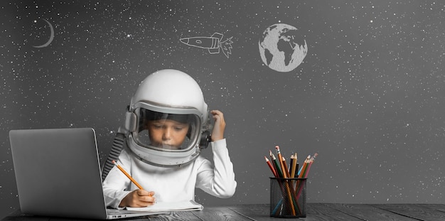 El niño estudia a distancia en la escuela usando un casco de astronauta de regreso a la escuela