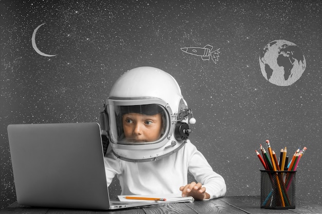 El niño estudia a distancia en la escuela, usando un casco de astronauta. De vuelta a la escuela