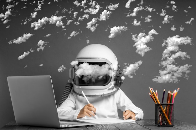 Foto el niño estudia a distancia en la escuela, usando un casco de astronauta. de vuelta a la escuela