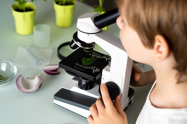 Foto niño estudia plantas bajo un microscopio emociones de alegría y sonrisa