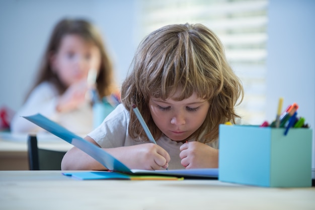 Niño estudiando en la escuela escolar haciendo los deberes en la educación en el aula para niños