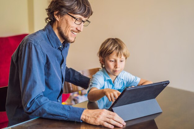 Niño estudiando en línea en casa usando una tableta El padre lo ayuda a aprender Estudiar durante la cuarentena Virus pandémico global covid19