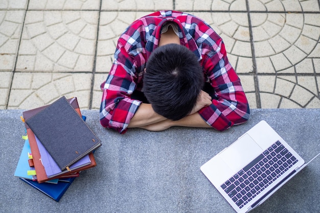 Niño estudiante cansado de estudiar sentarse y descansar en el escritorio de la escuela