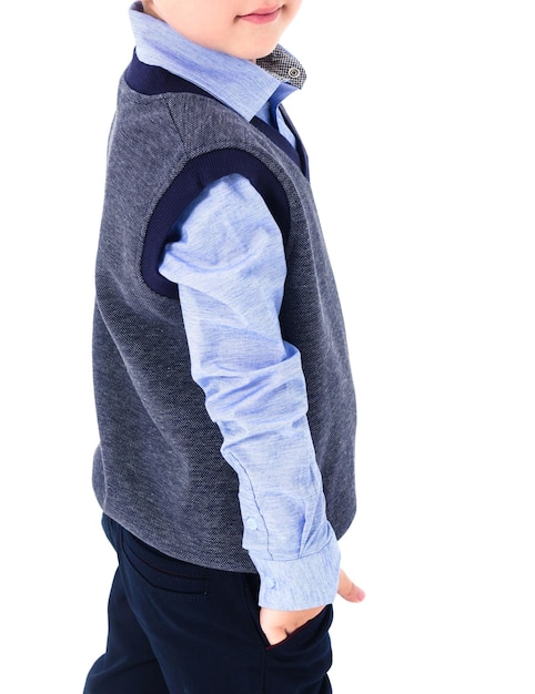 Niño estudiante de escuela primaria posando en uniforme escolar El niño lleva una camisa azul y un chaleco Foto vertical