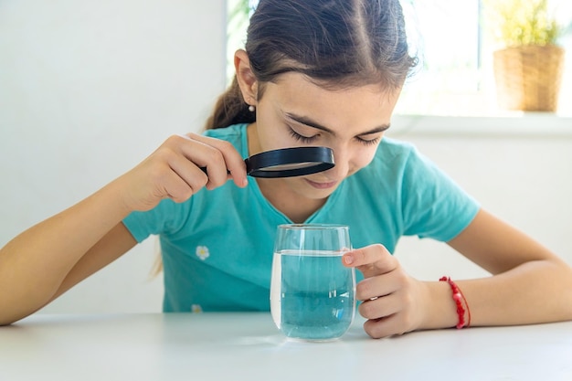 El niño examina el agua bajo una lupa Enfoque selectivo