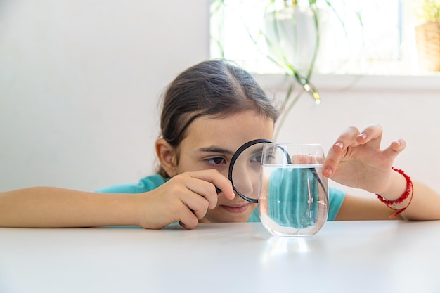 El niño examina el agua bajo una lupa Enfoque selectivo