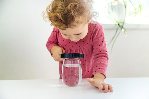 El niño examina el agua bajo una lupa Enfoque selectivo