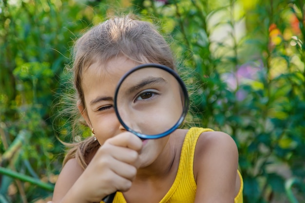 El niño examina las plantas con una lupa. Enfoque selectivo.