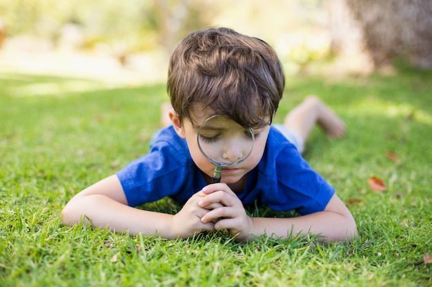 Niño examinando el césped con una lupa