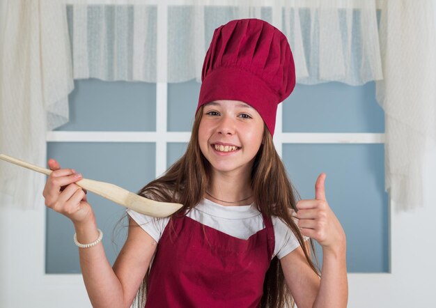 Foto un niño exitoso con sombrero de chef sostiene el éxito de una cuchara de madera