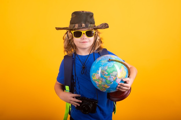 Niño explorador con sombrero de explorador y mochila en el estudio de fondo amarillo