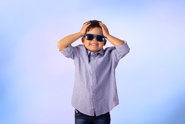 Niño con expresiones faciales en una foto de estudio sobre fondo de color.