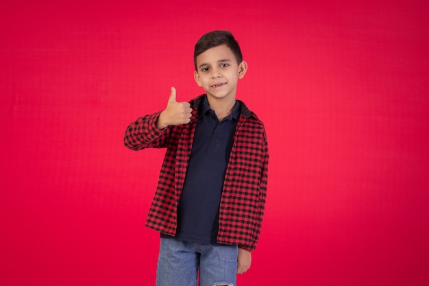 Niño con expresiones faciales en una foto de estudio sobre fondo rojo.