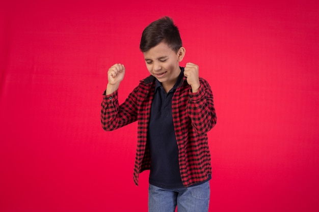 Niño con expresiones faciales en una foto de estudio sobre fondo rojo.