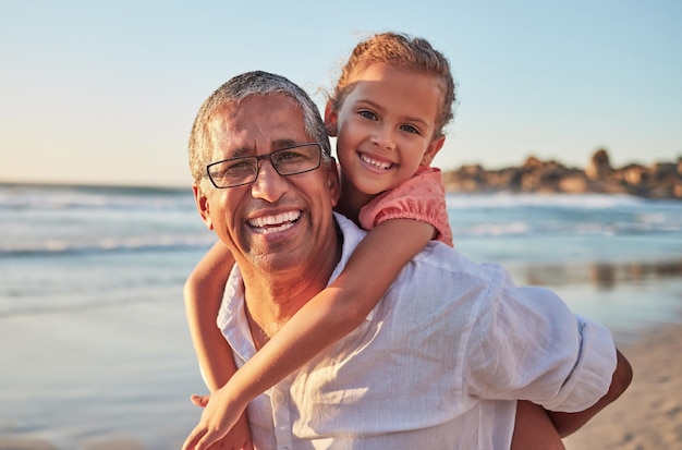 Niño de familia y abuelo en vacaciones en la playa con sonrisa amor y diversión anciano llevando a la niña en la espalda en un viaje de verano tropical Abuelo activo y niño feliz riendo durante el paseo a cuestas por mar