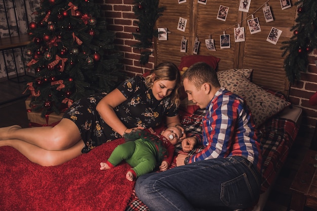 Niño de familia feliz celebrando el año nuevo y la Navidad en el árbol de Navidad decorado y guirnaldas