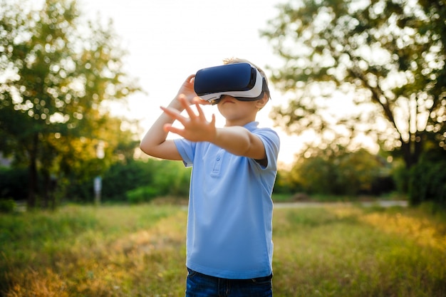 Niño fascinado con gafas de realidad virtual VR. al aire libre