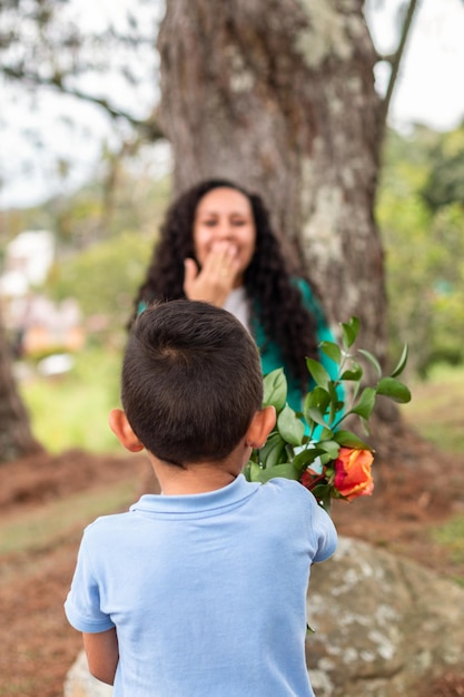 Niño felicitando a su madre por el Día de la Madre al aire libre