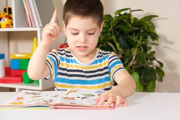 Un niño feliz de 4 años mira un libro con fotos.