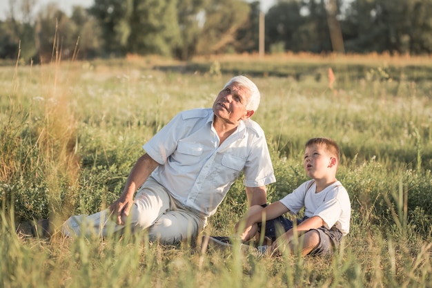 Niño feliz con abuelo jugando en la pradera