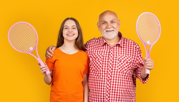 Niño feliz con abuelo con raqueta de bádminton sobre fondo amarillo