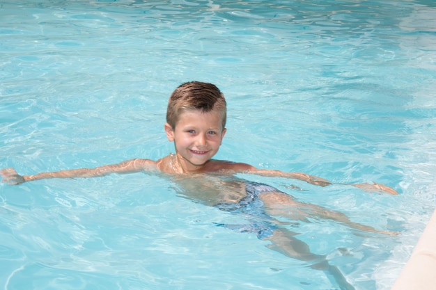 Niño feliz en el agua de la piscina durante las vacaciones de verano