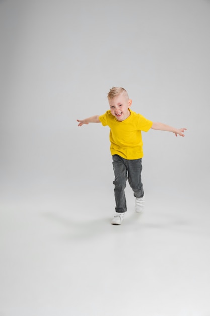 Niño feliz aislado en la pared. Parece feliz, alegre. Copyspace Infancia, educación, emociones, concepto de expresión facial. Saltando alto, jugando divirtiéndote