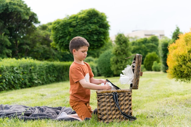 Niño feliz al aire libre en verano con una cesta de picnic.