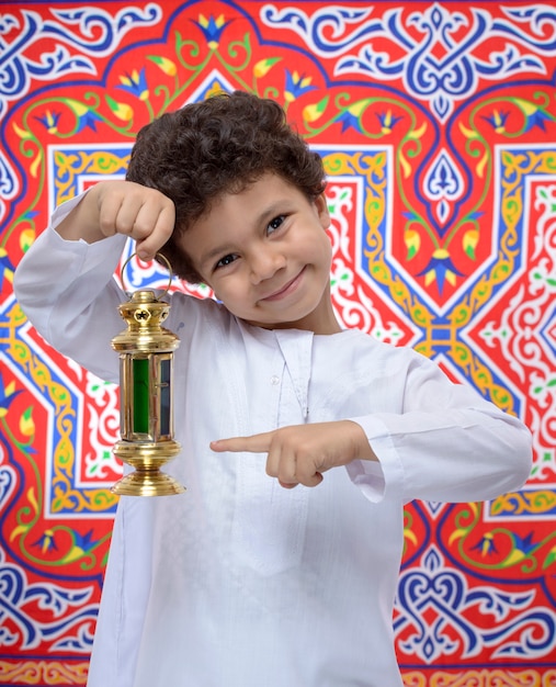 Foto niño feliz apuntando a la linterna de ramadán