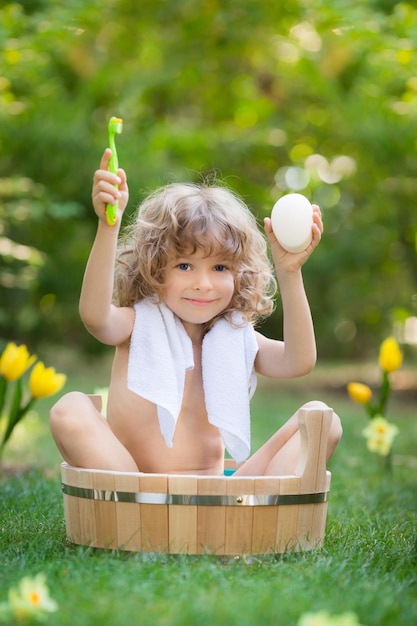 Niño feliz bañándose al aire libre en la hierba verde en el jardín de primavera