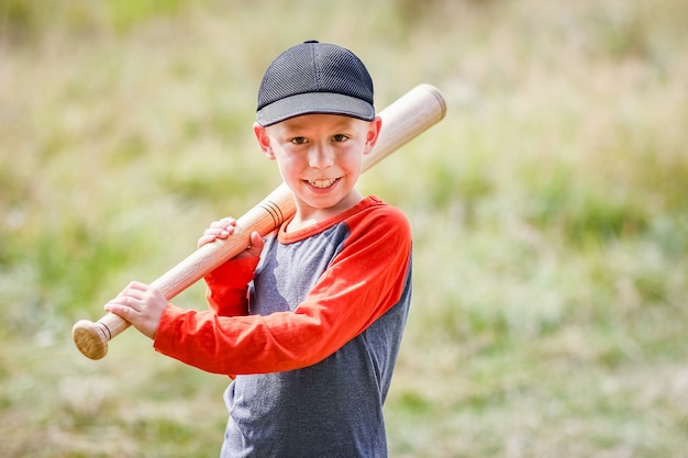 Un niño feliz con un bate de béisbol en el concepto de naturaleza en el parque